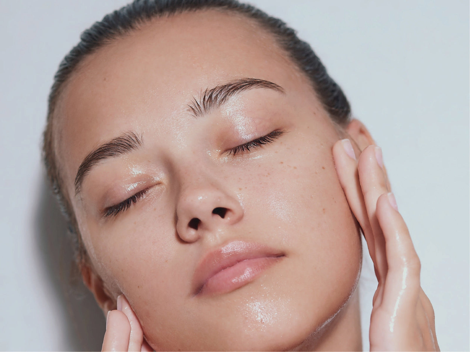 a woman touching her face on a grey background